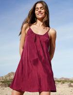 Woman wearing a red mini dress against a desert background.