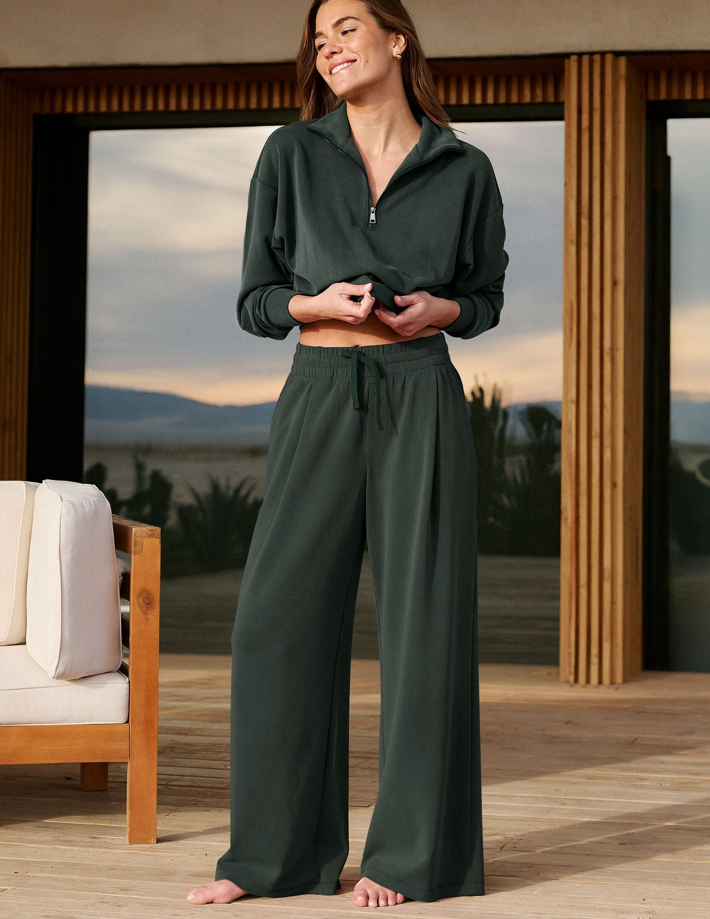 Woman wearing a green sweatshirt and green pants standing in front of a house.