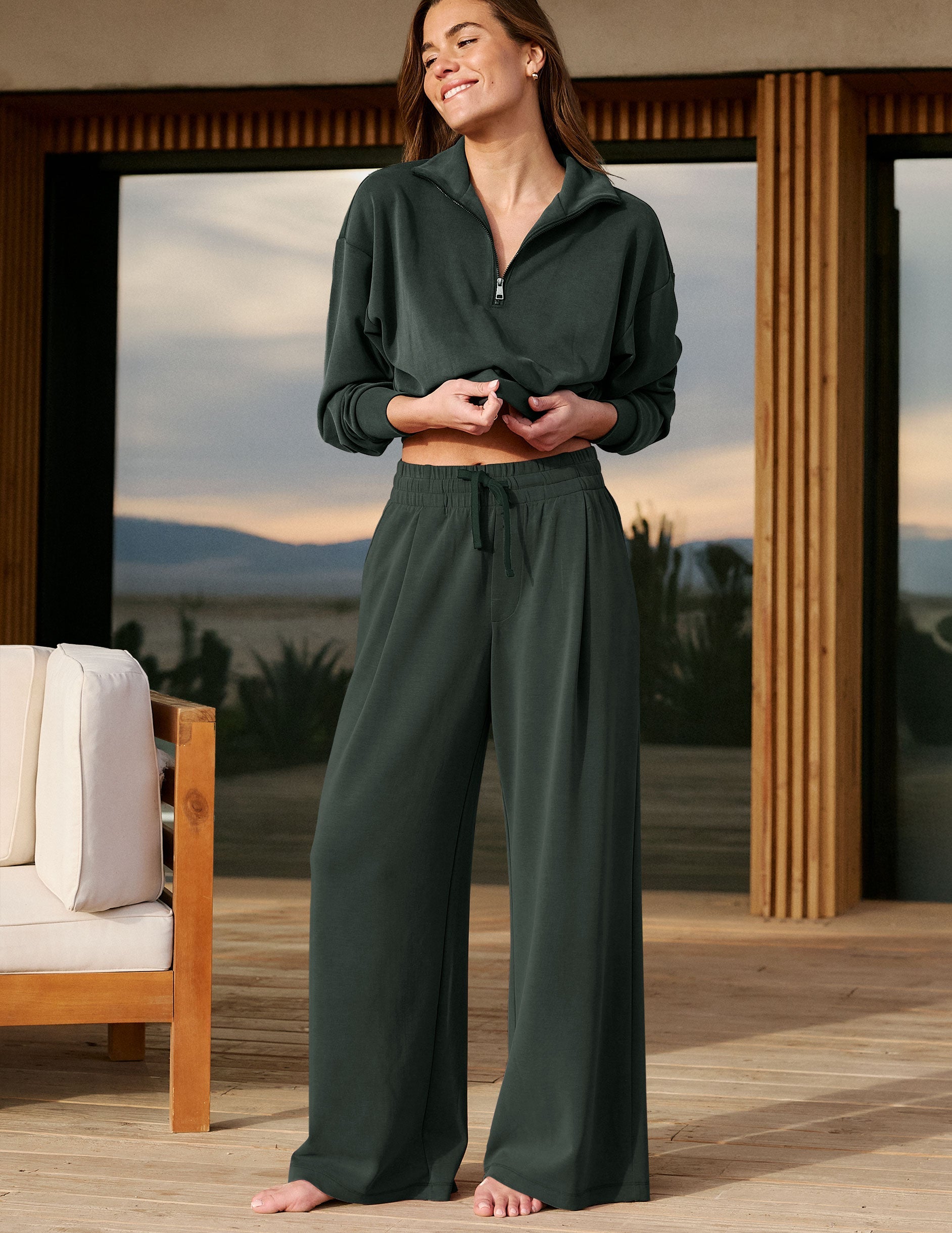 Woman wearing a green sweatshirt and green pants standing in front of a house.