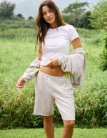 Woman wearing Beige Fade Out Low-Rise Bermuda Short™ with a white cropped t-shirt and matching draped sweatshirt.