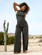 Woman in a green tank and pants standing in a desert-like setting with cacti.