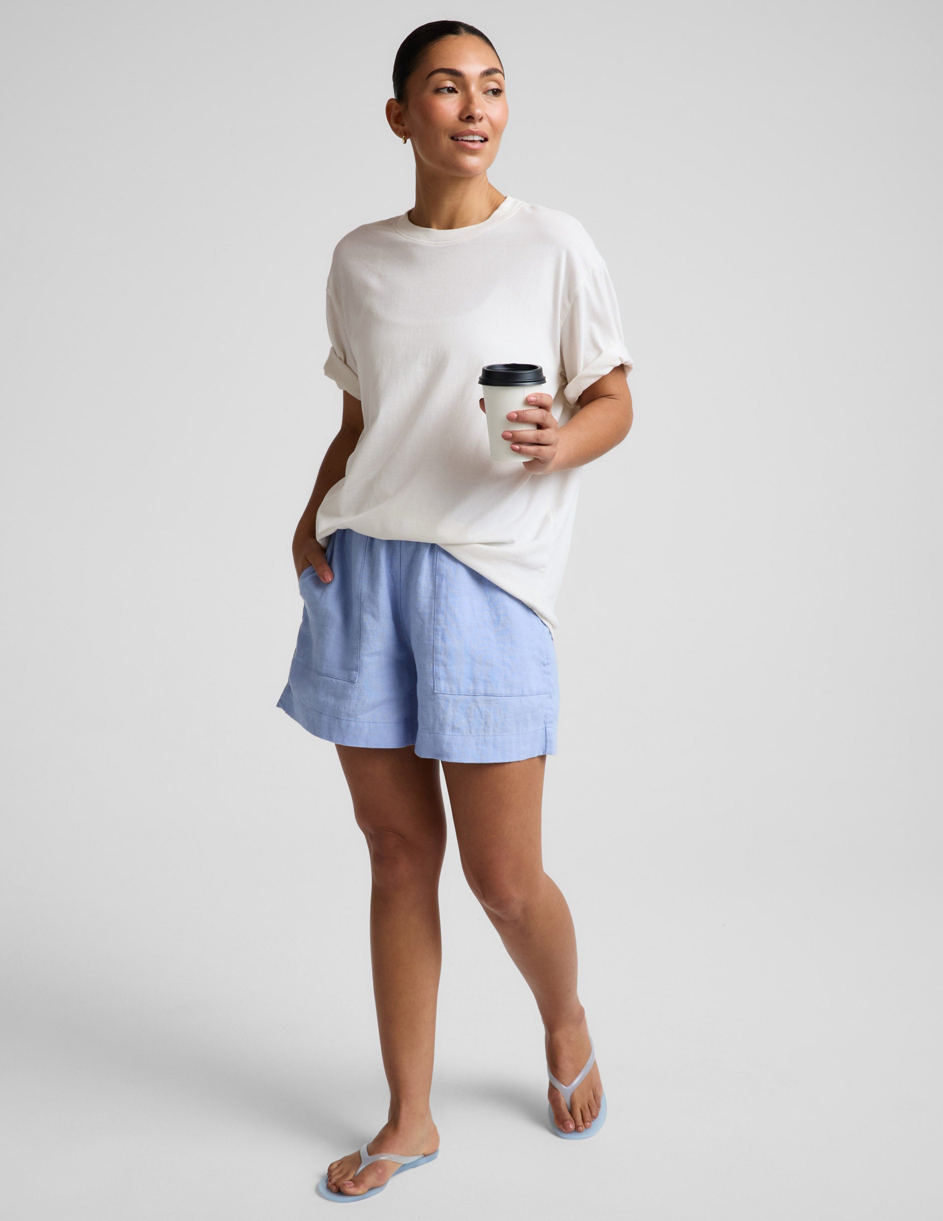 Person wearing light blue shorts and a white top on a plain background.