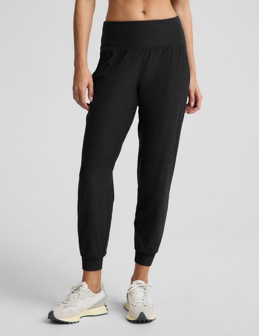 Woman wearing a black bra and black joggers against a plain background.