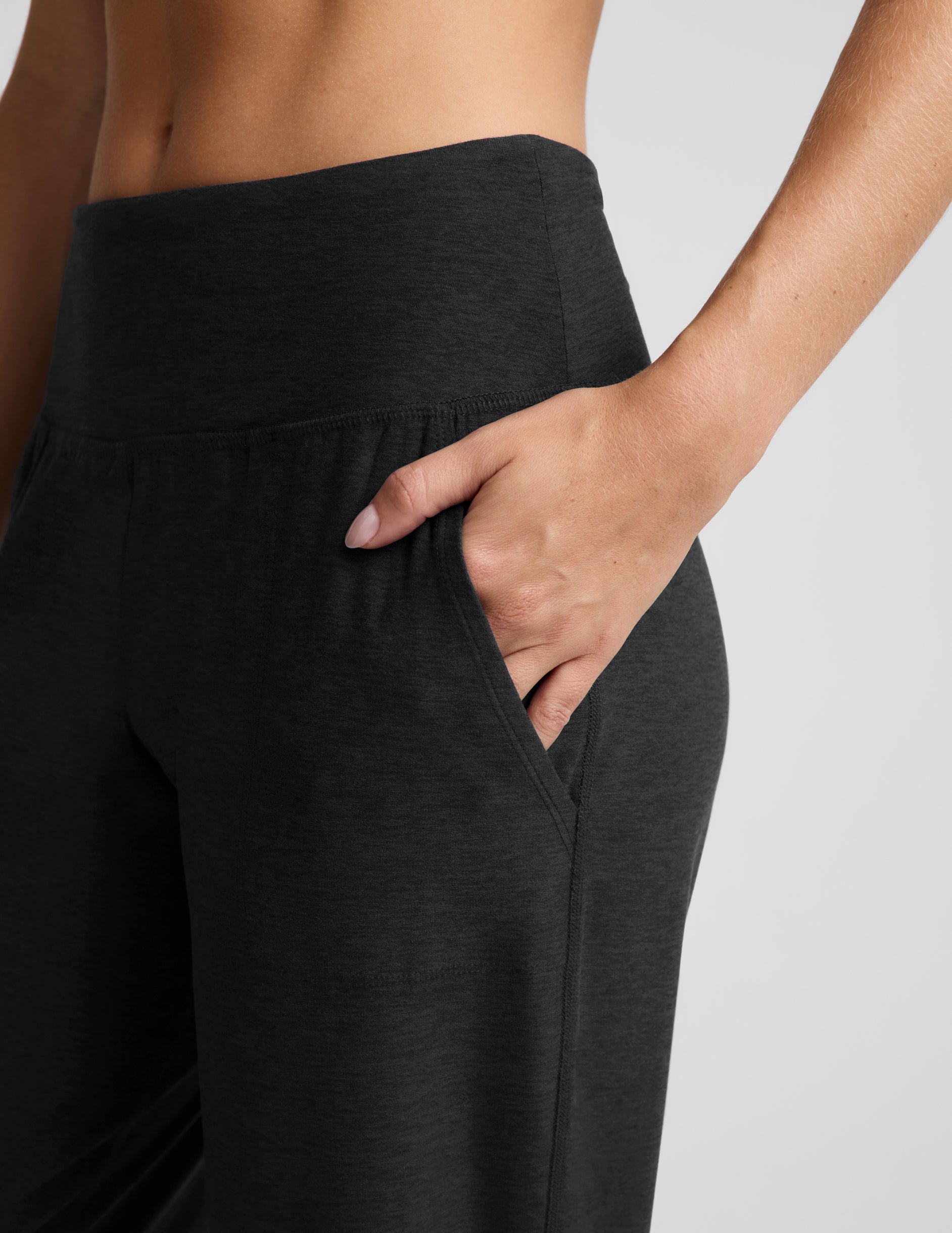 Woman wearing a black bra and black joggers against a plain background.