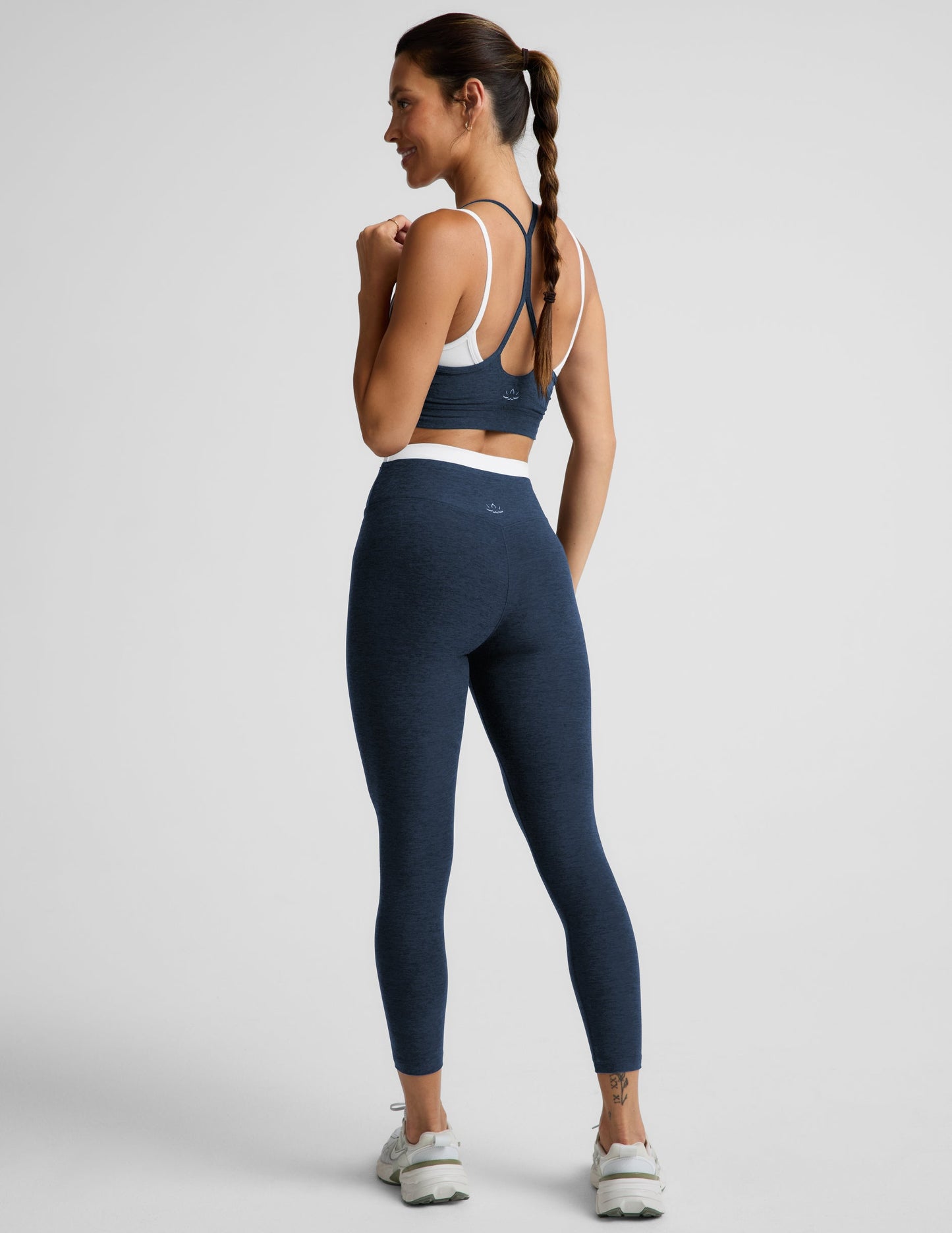 Woman wearing a navy sports bra and leggings set on a plain background.