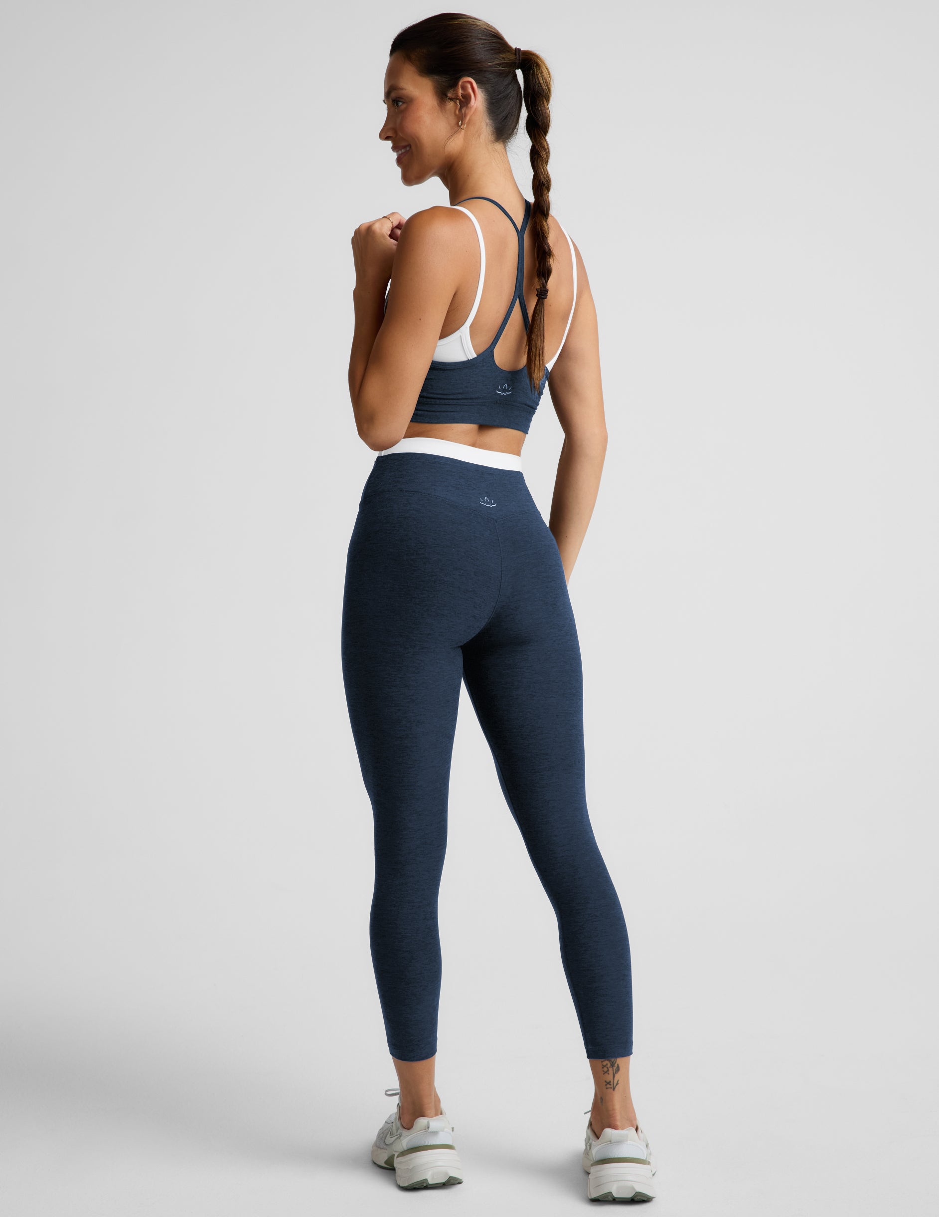 Woman wearing a navy sports bra and leggings set on a plain background.