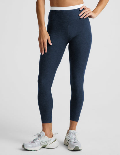 Woman wearing a navy sports bra and leggings set on a plain background.
