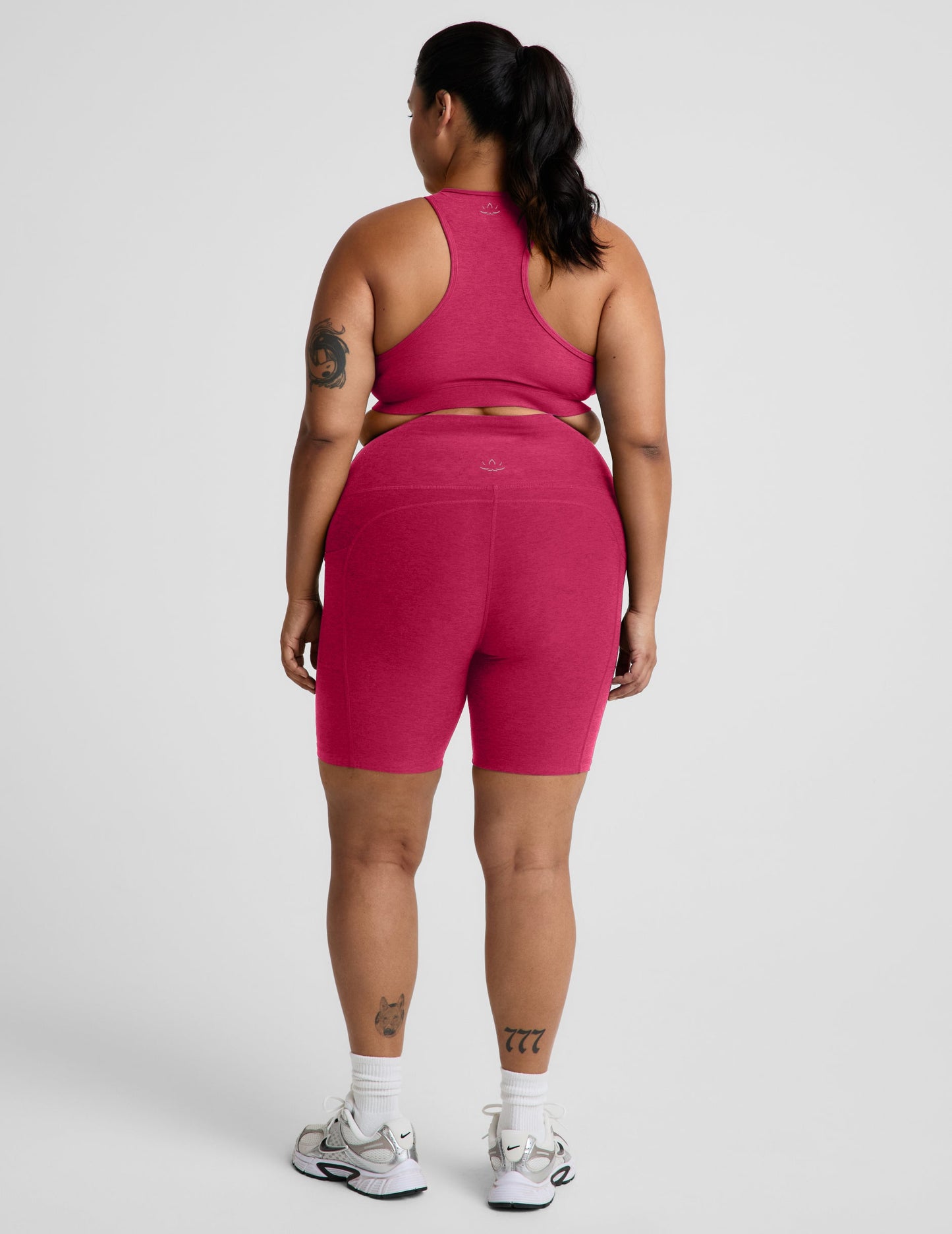 Rear view of woman wearing Pink Spacedye™ Keep Pace 7" Pocket Short paired with a matching racerback bra and sneakers.