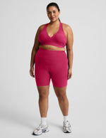 Woman wearing Pink Spacedye™ Keep Pace 7" Pocket Short paired with a matching sports bra and white sneakers.