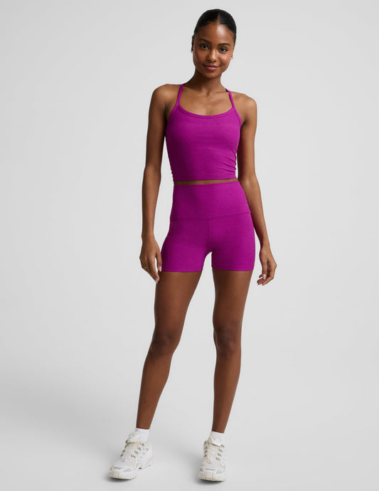 Woman wearing a purple cropped racerback tank and 3" biker shorts against a plain background.