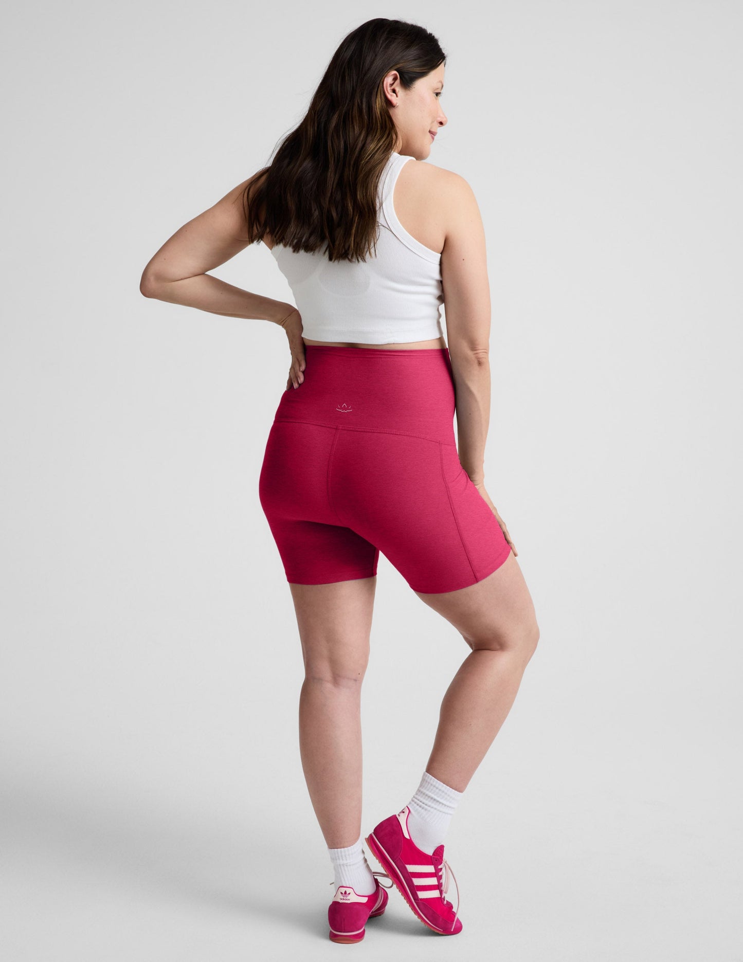 Rear view of woman wearing Pink Spacedye™ Keep Pace 5" Maternity Pocket Biker Short with a white cropped tank top.