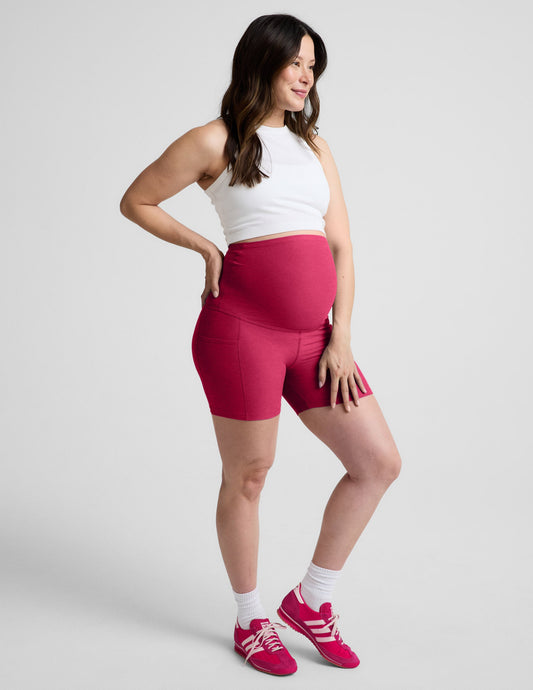 Woman wearing Pink Spacedye™ Keep Pace 5" Maternity Pocket Biker Short with side pockets, paired with a white tank top.