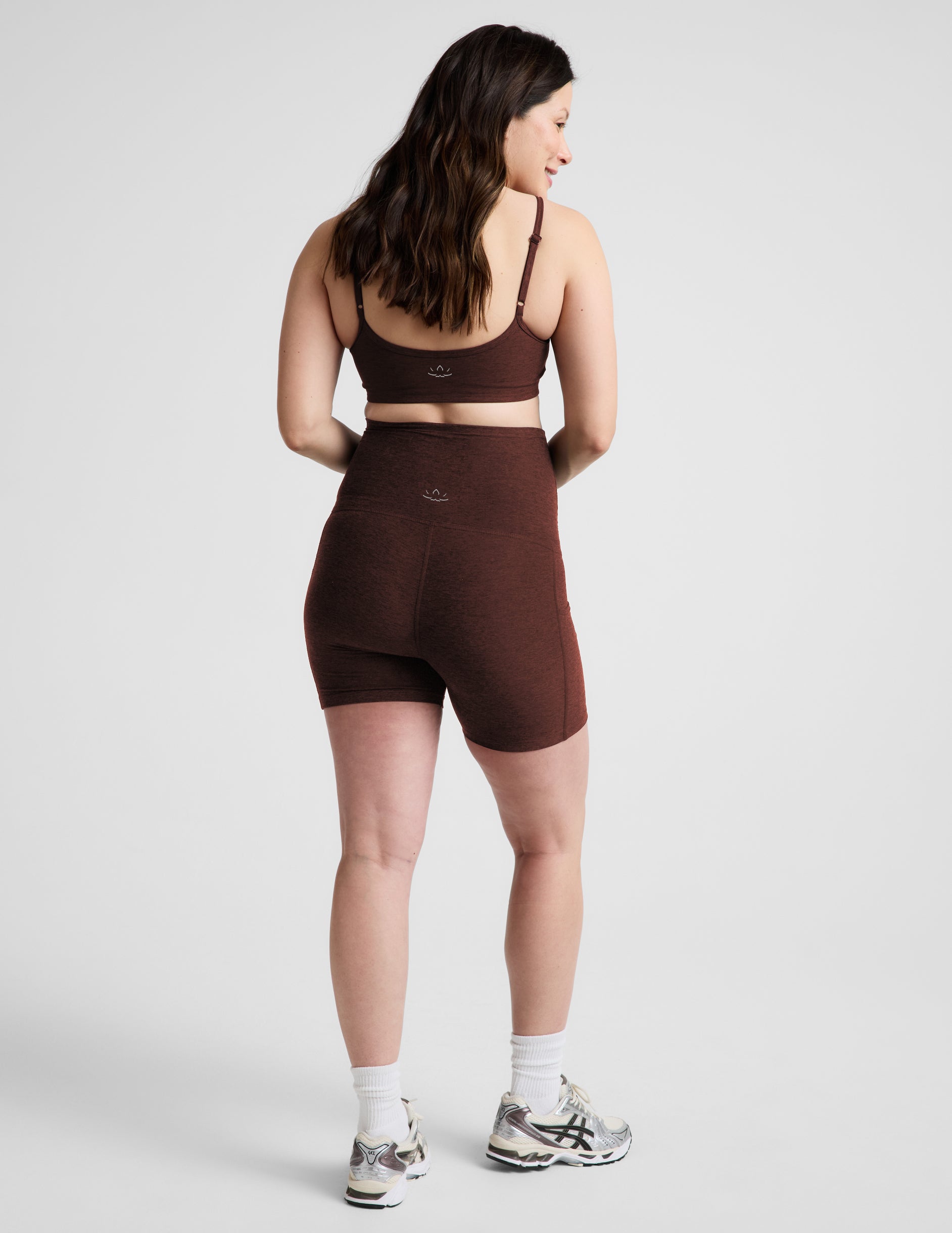 Woman wearing Brown Spacedye™ Keep Pace 5" Maternity Pocket Biker Short, rear view, paired with a matching bra top.