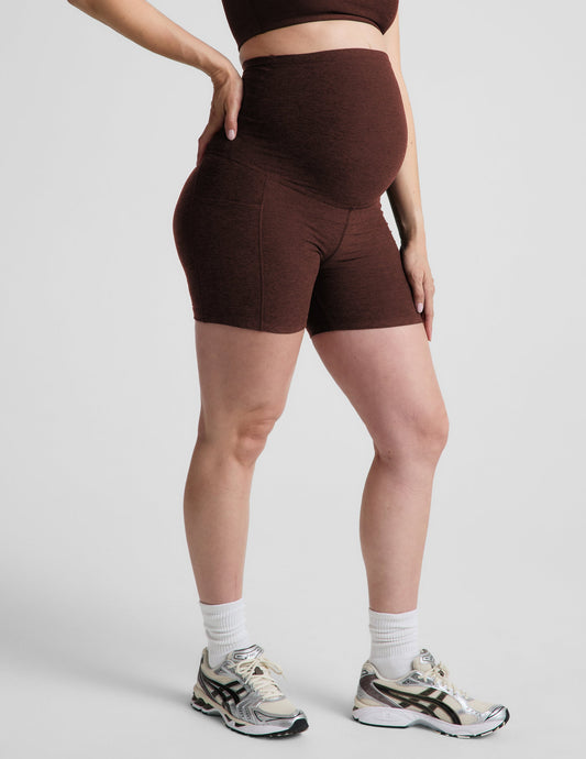 Woman wearing Brown Spacedye™ Keep Pace 5" Maternity Pocket Biker Short paired with a matching top and cream sneakers.