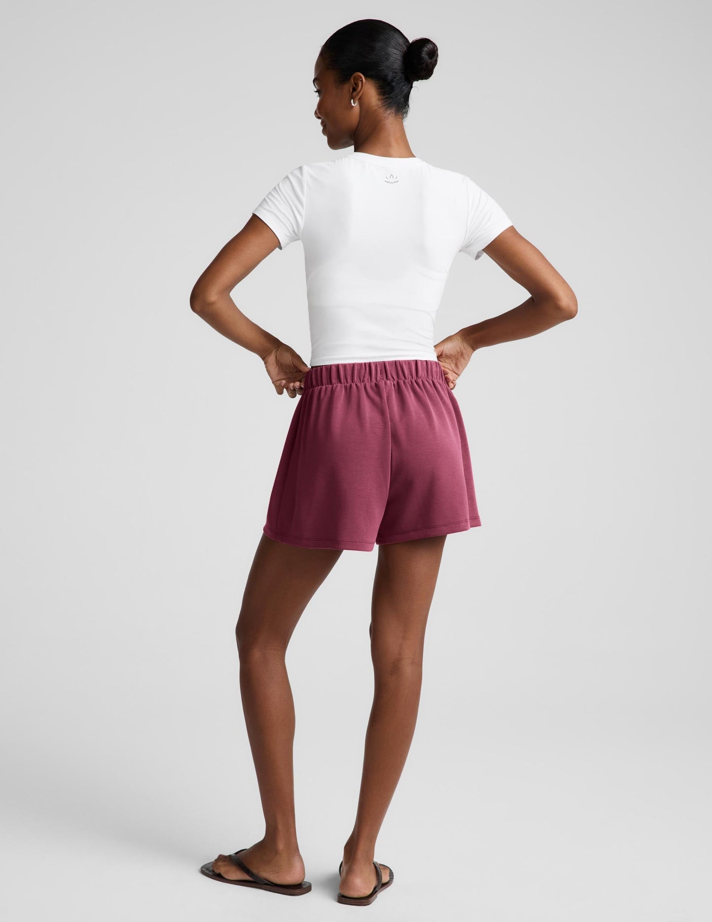 Woman wearing a white t-shirt and mauve skort against a plain background.