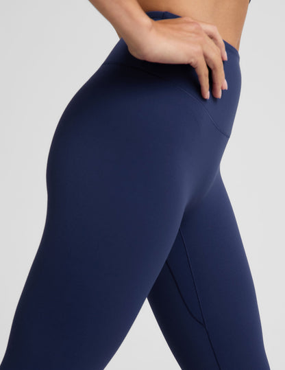 Woman wearing a blue cropped tank and blue midi leggings against a plain background.