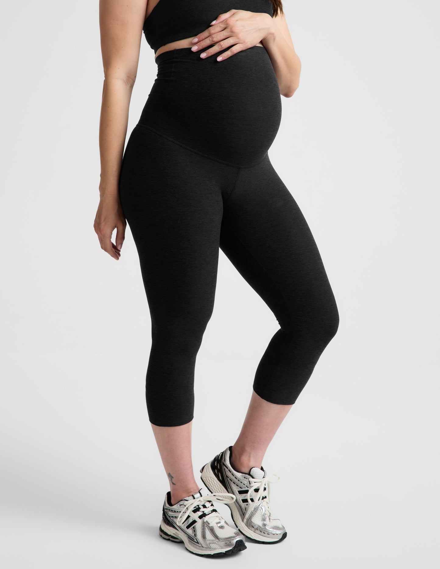 Woman wearing Black Spacedye™ Love The Bump Maternity 20.5" Capri Legging paired with a black crop top and sneakers.