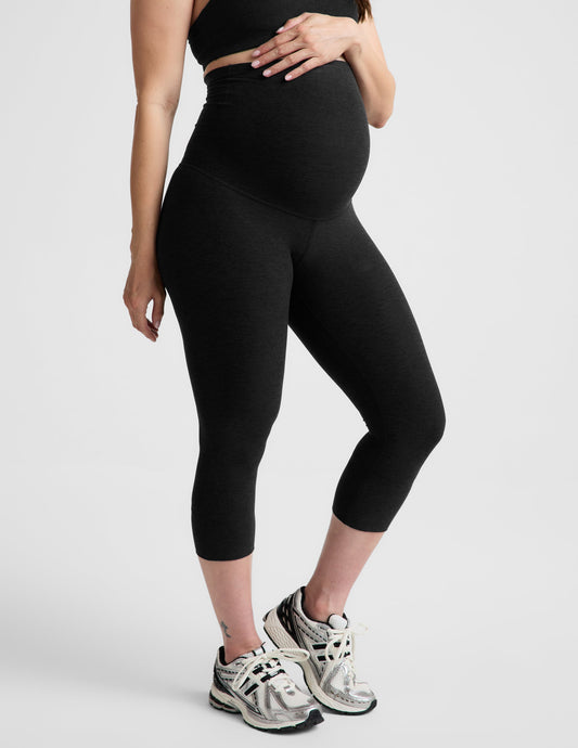 Woman wearing Black Spacedye™ Love The Bump Maternity 20.5" Capri Legging paired with a black crop top and sneakers.