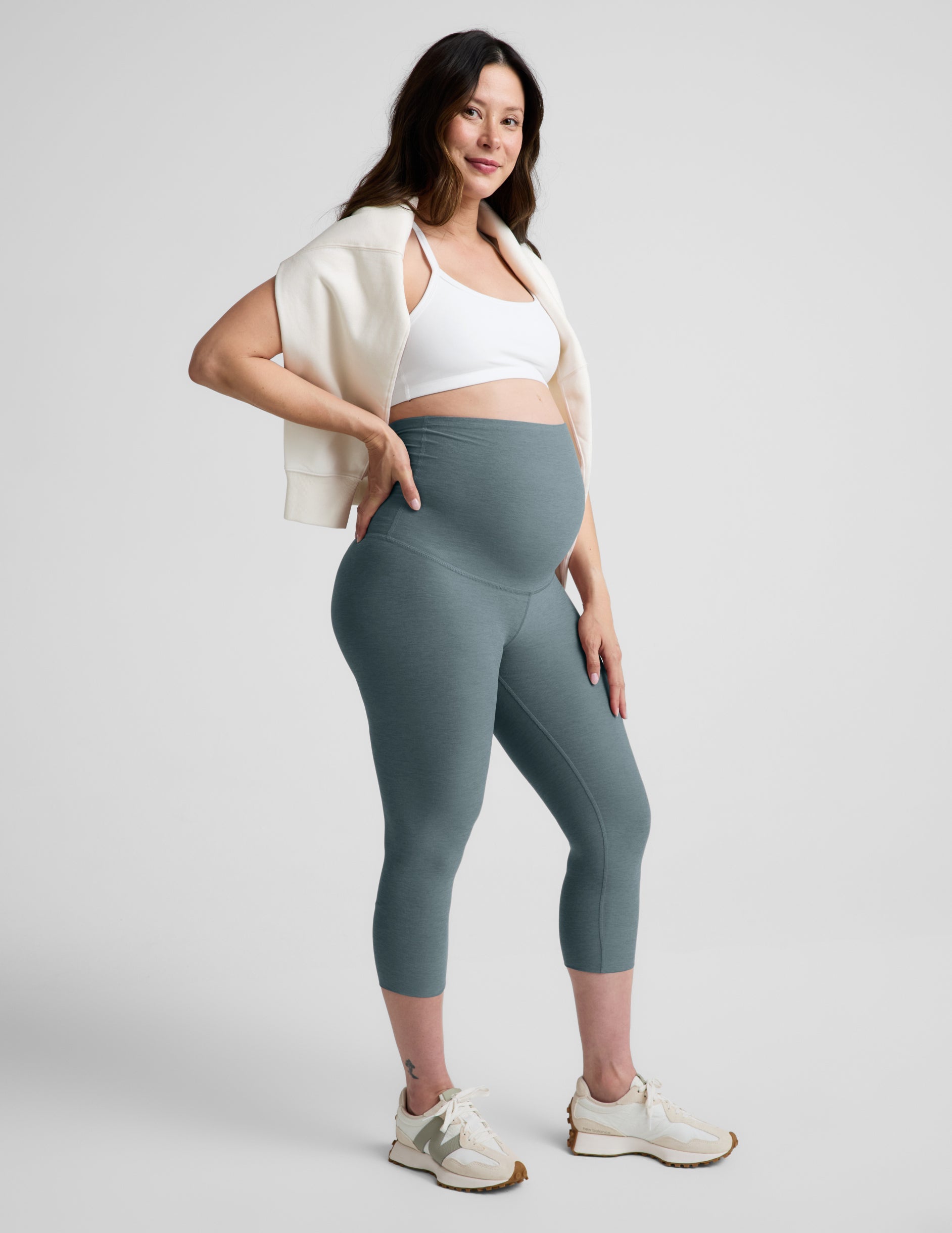 Woman wearing Blue Spacedye™ Love The Bump Maternity 20.5" Capri Legging over her bump with a white sports bra.