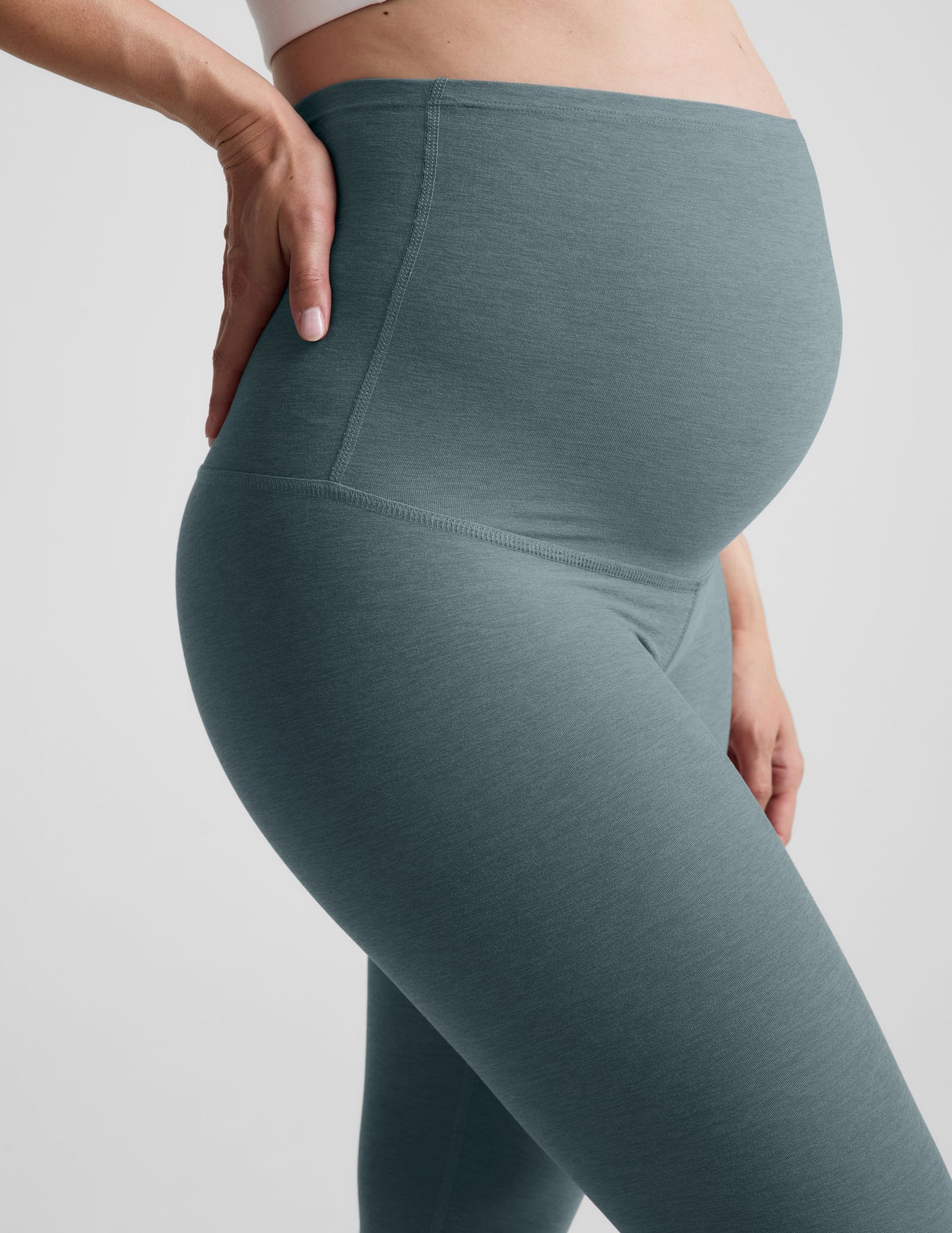 Woman wearing Blue Spacedye™ Love The Bump Maternity 20.5" Capri Legging over her belly, shown from a side profile.