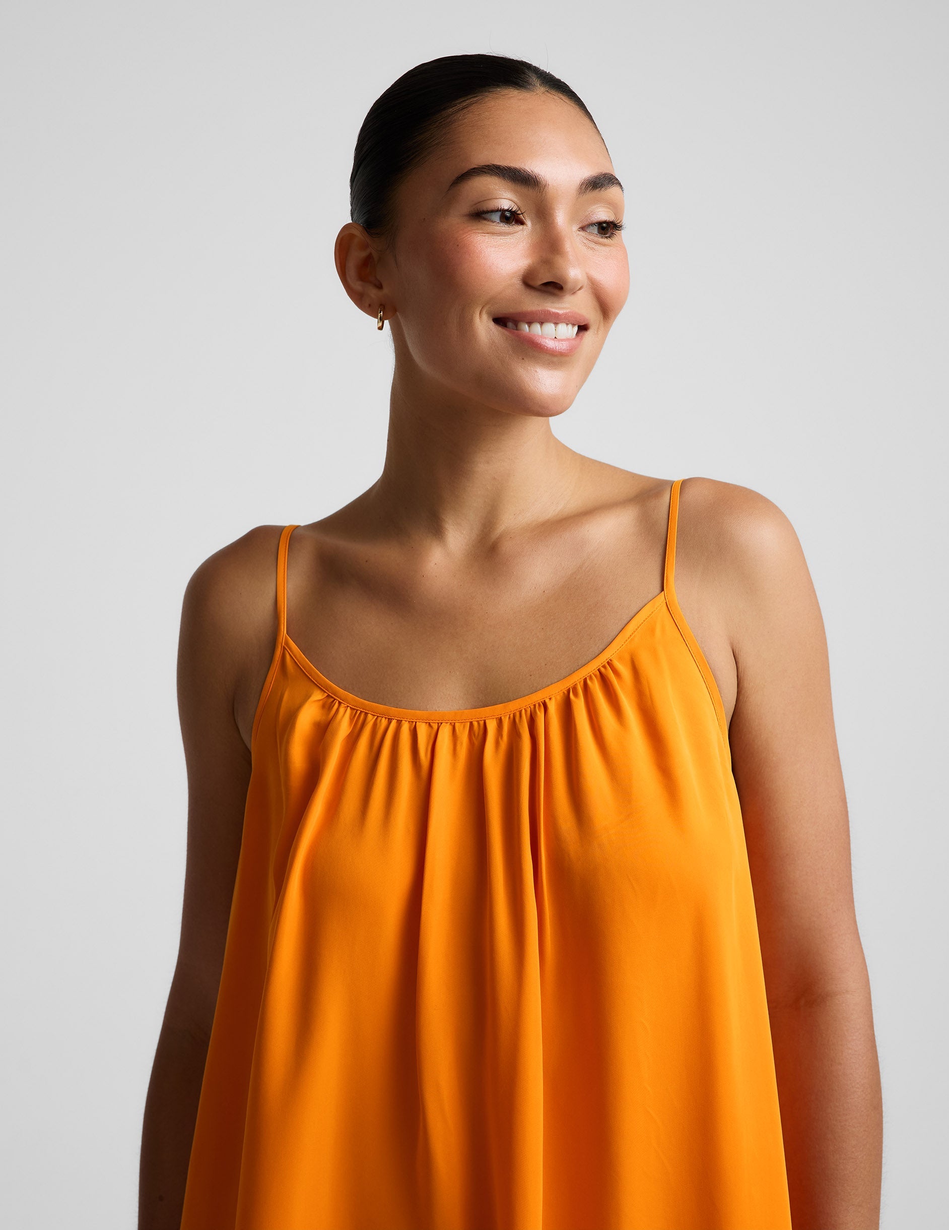 Woman wearing an orange maxi cupro dress against a plain background.