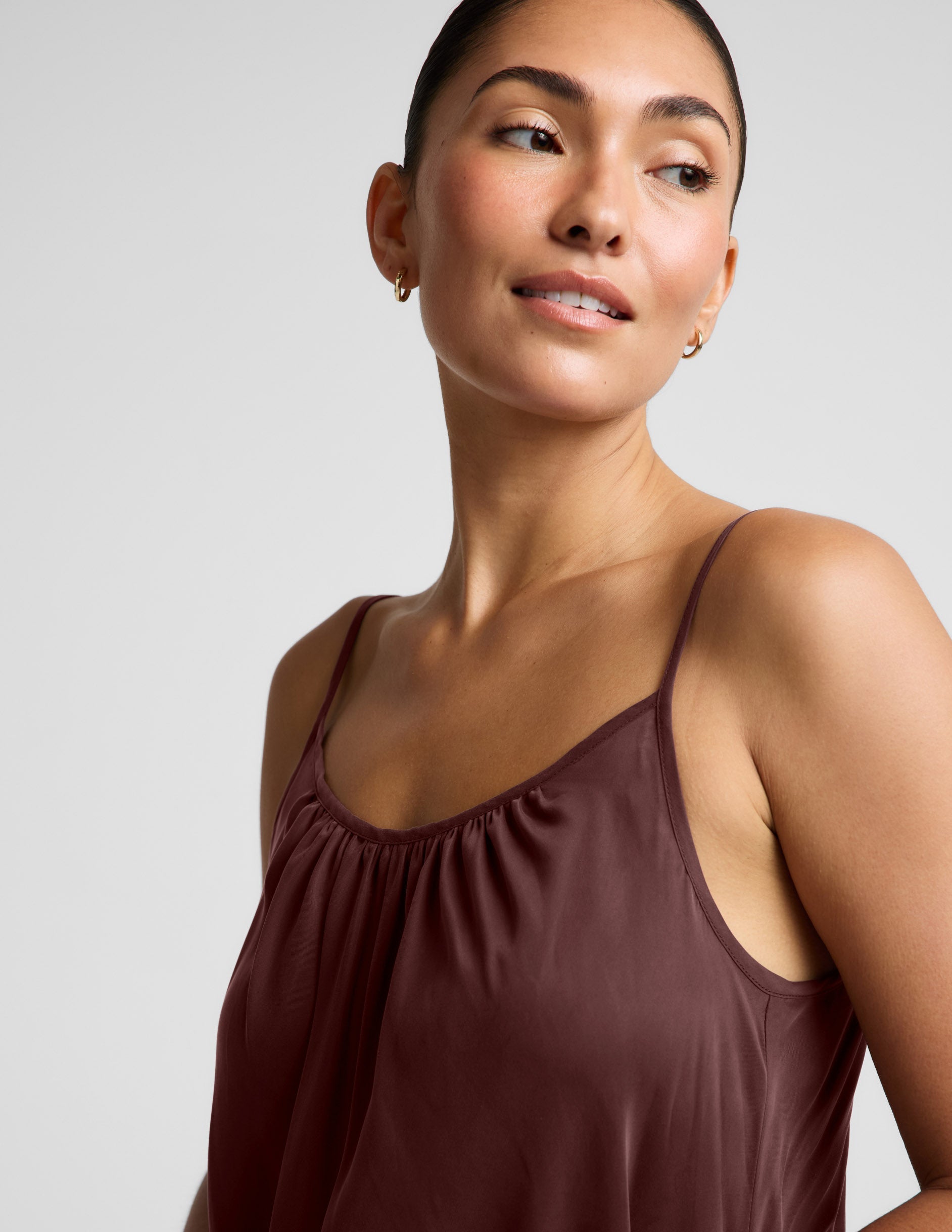 Woman wearing a brown cupro mini dress and black sandals against a plain background.