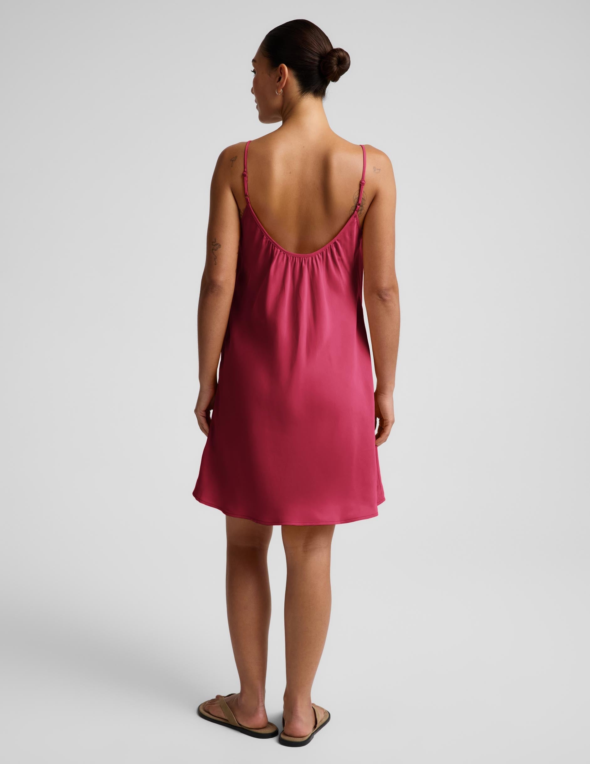 Woman wearing a red mini tank dress against a plain background.