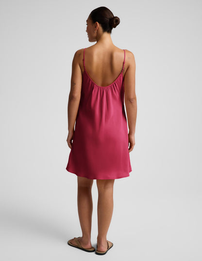 Woman wearing a red mini tank dress against a plain background.