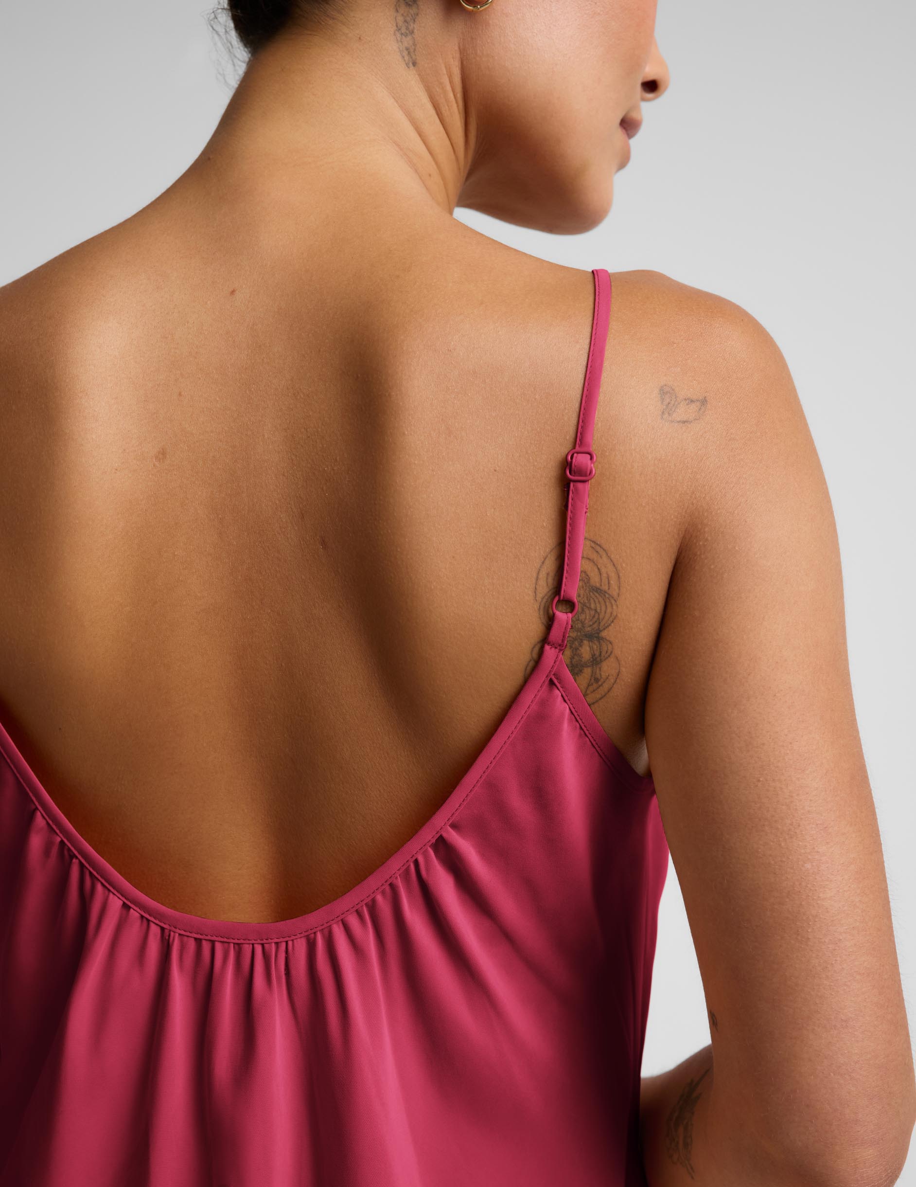 Woman wearing a red mini tank dress against a plain background.