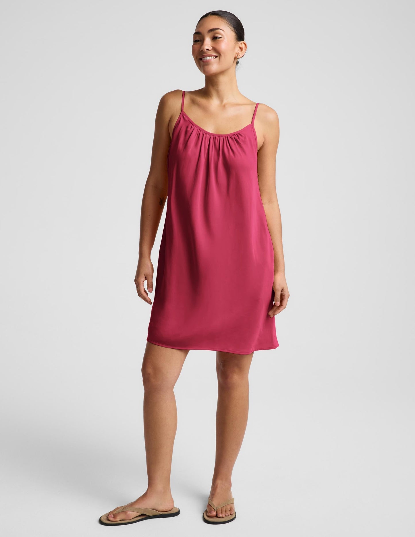 Woman wearing a red mini tank dress against a plain background.