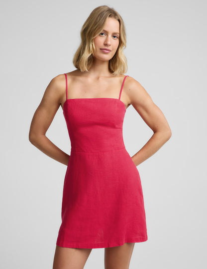 Woman wearing a red mini linen dress against a plain background.