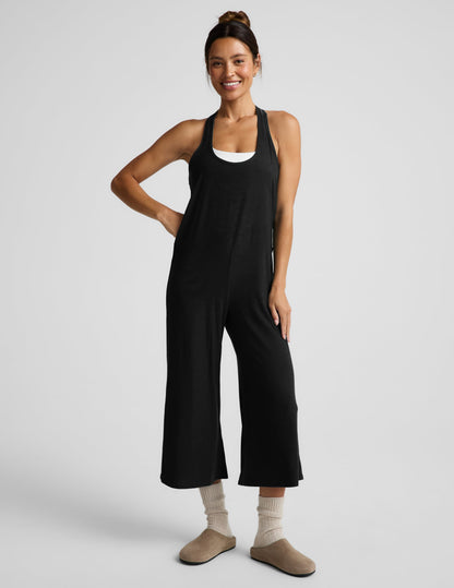 Woman wearing a black tank jumpsuit against a plain background.