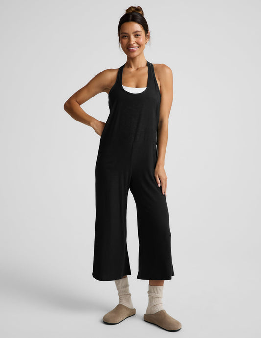 Woman wearing a black tank jumpsuit against a plain background.