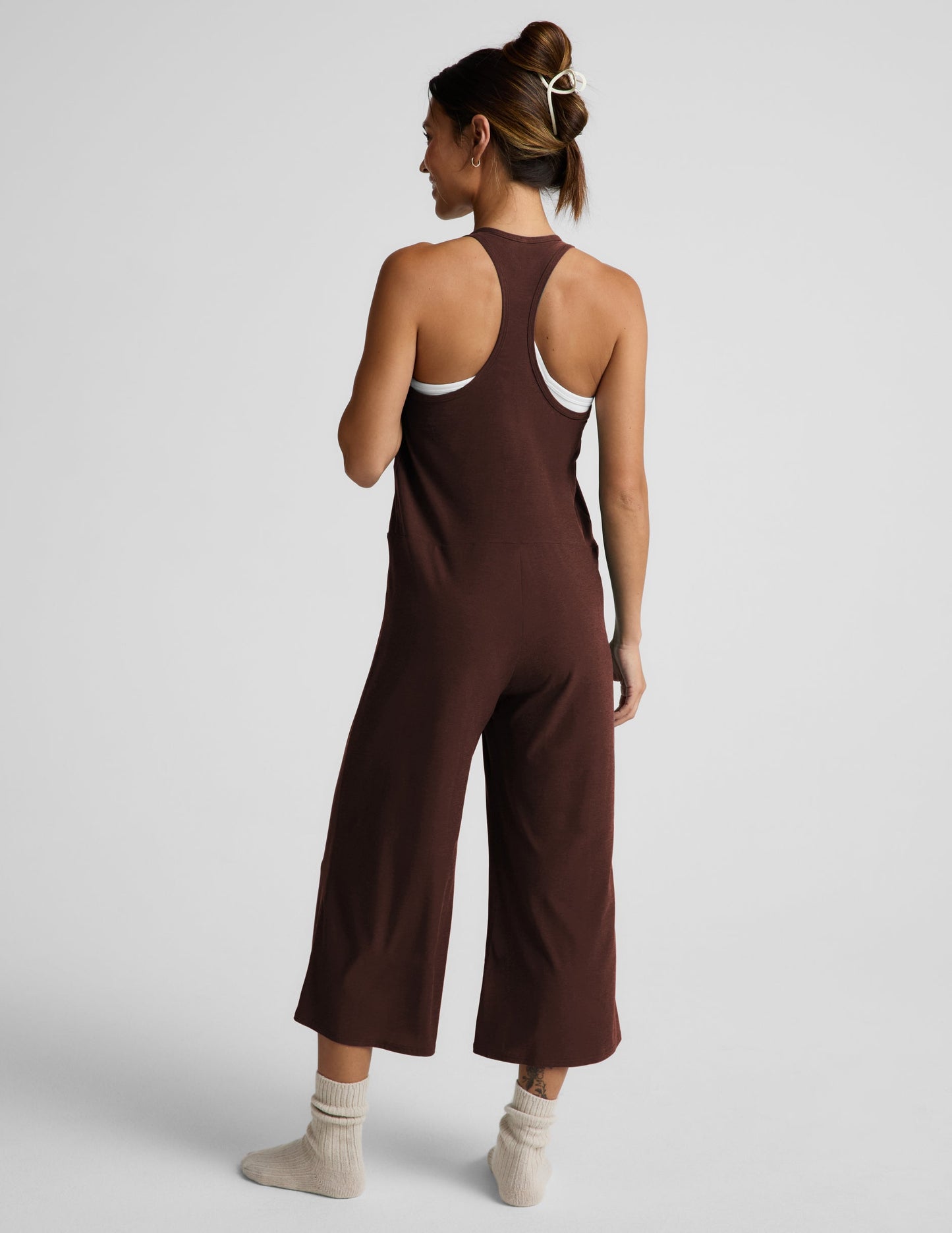 Woman wearing a brown jumpsuit on a white background.