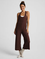 Woman wearing a brown jumpsuit on a white background.