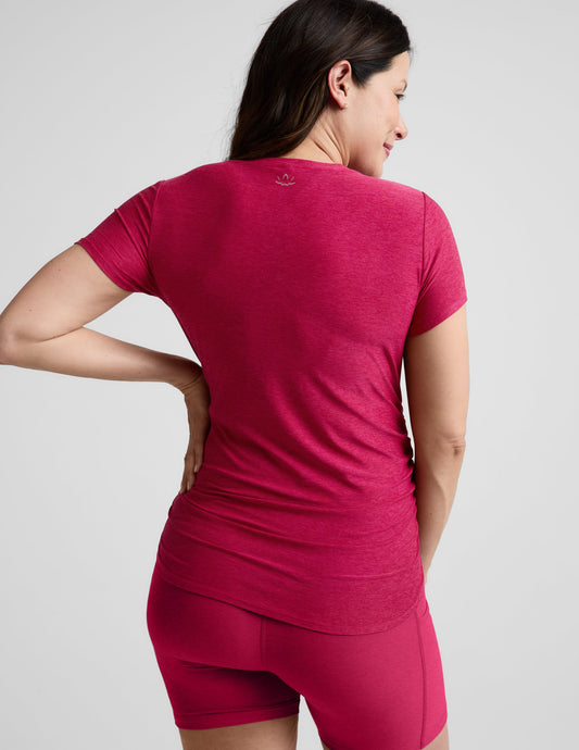 Pregnant woman wearing a red maternity t-shirt and shorts against a plain background.