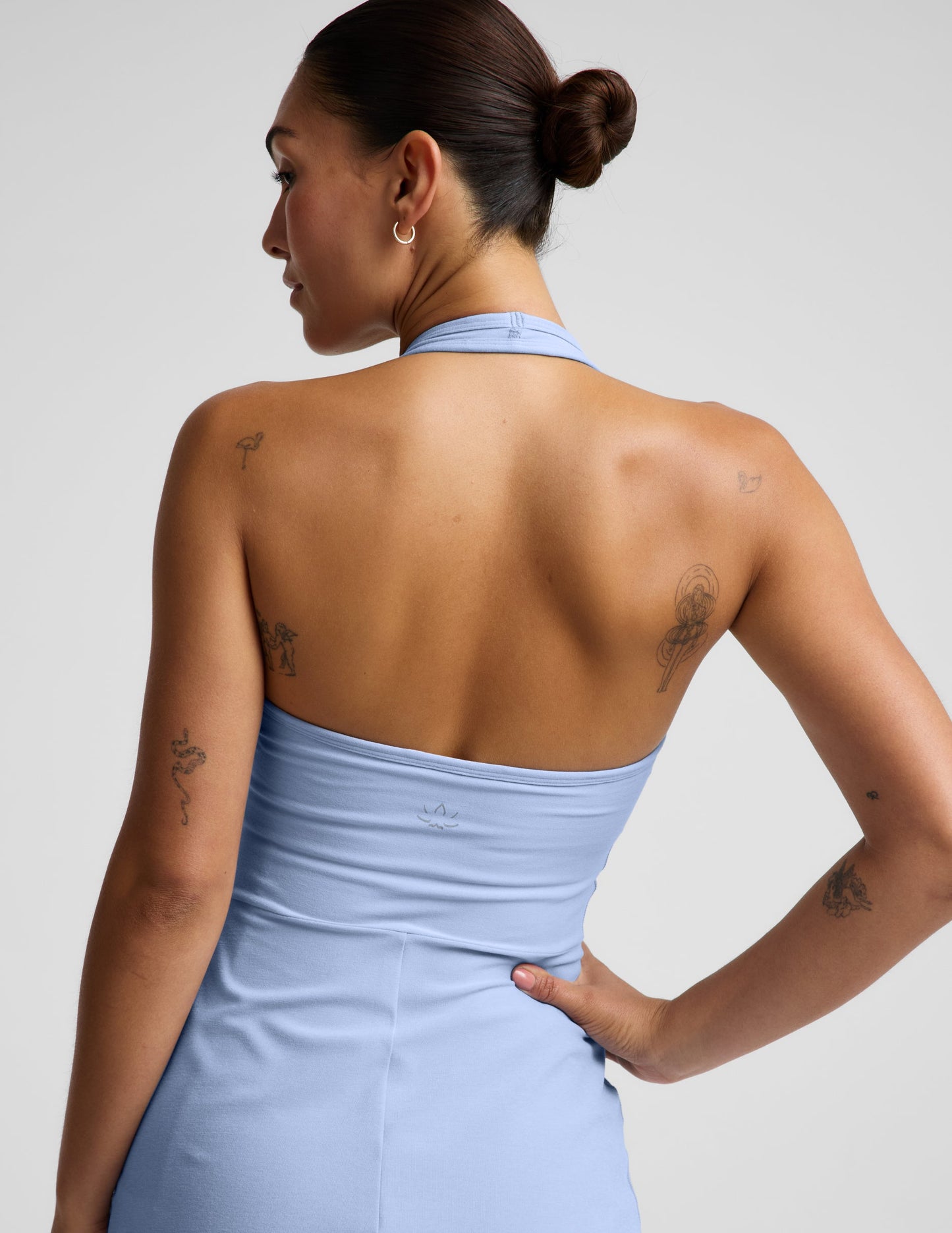 Woman wearing a light blue halter mini dress against a plain background.