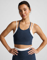 Woman wearing a navy layered bra and leggings against a plain background.