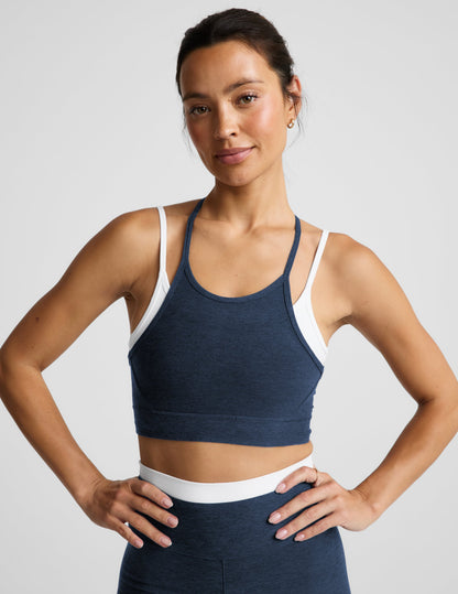 Woman wearing a navy layered bra and leggings against a plain background.
