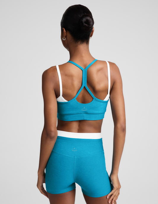 Woman wearing a blue and white layered bra and matching shorts against a plain background.