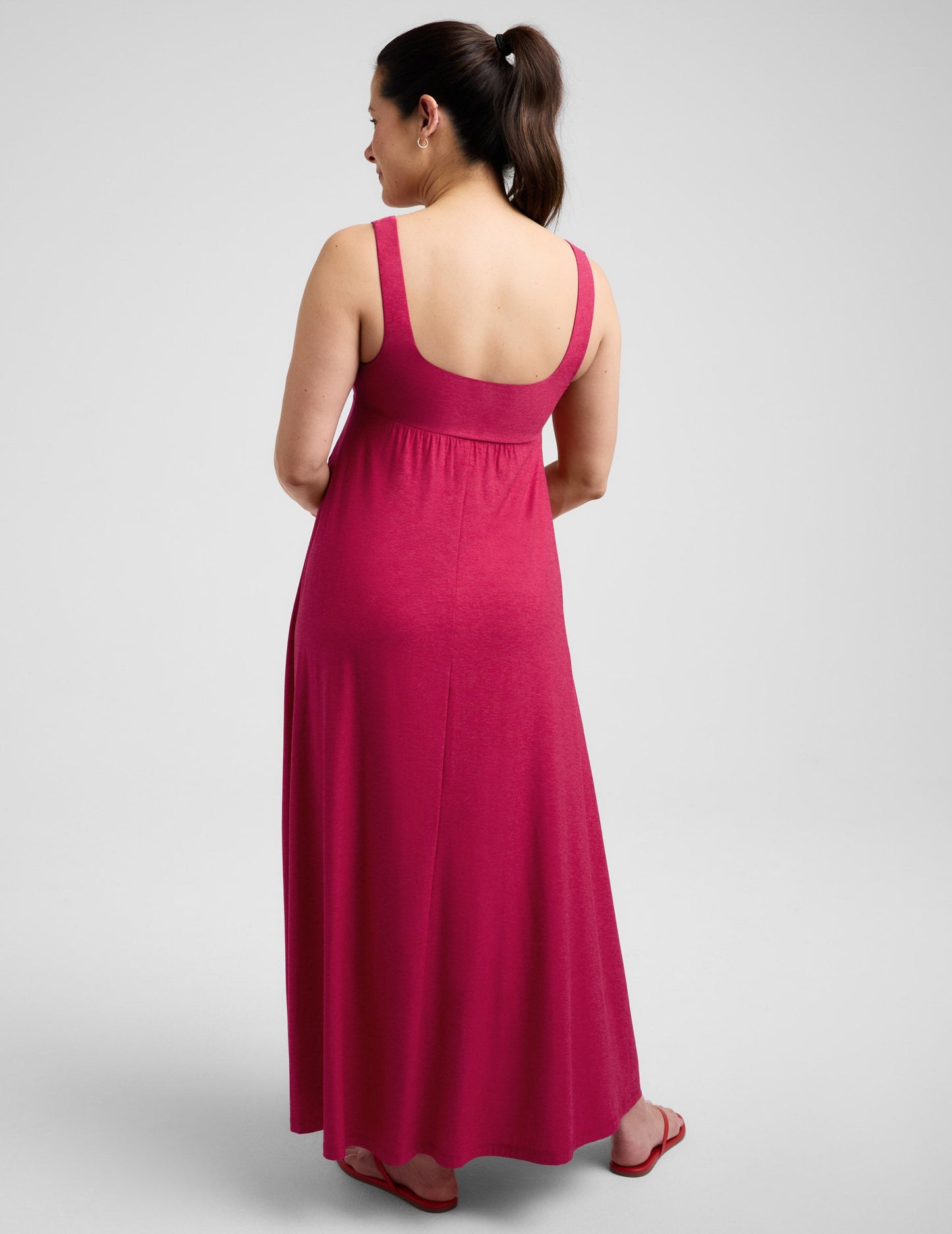 Pregnant woman wearing a red dress against a plain background.