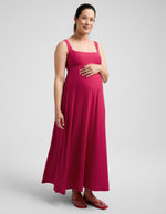Pregnant woman wearing a red dress against a plain background.