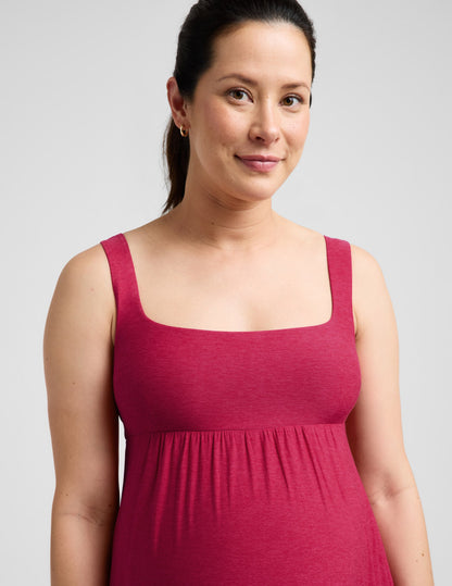 Pregnant woman wearing a red dress against a plain background.