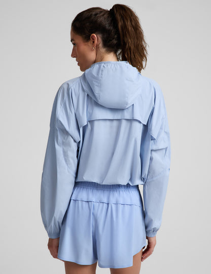 Woman wearing a light blue jacket and blue shorts against a plain background.