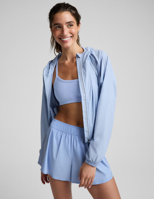 Woman wearing a light blue jacket and blue shorts against a plain background.