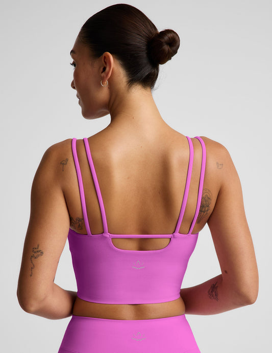 Woman wearing a purple cropped tank and purple biker shorts against a plain background.