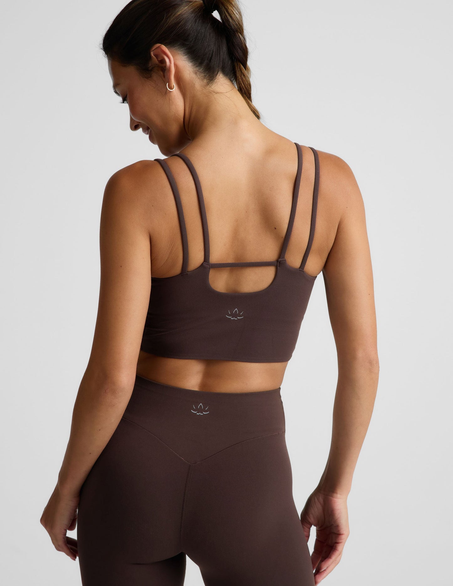Woman wearing a brown cropped tank and midi leggings on an plain studio background.