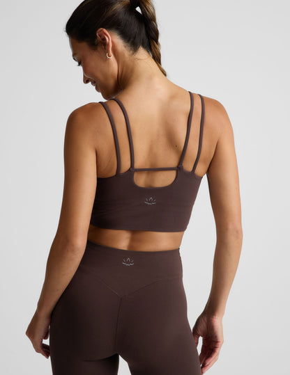 Woman wearing a brown cropped tank and midi leggings on an plain studio background.