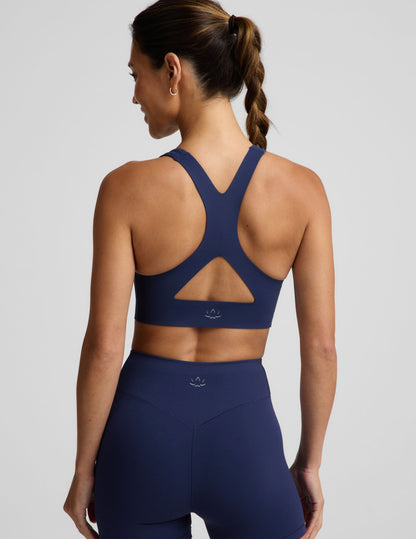 Woman wearing a blue sports bra and blue biker shorts against a plain background.