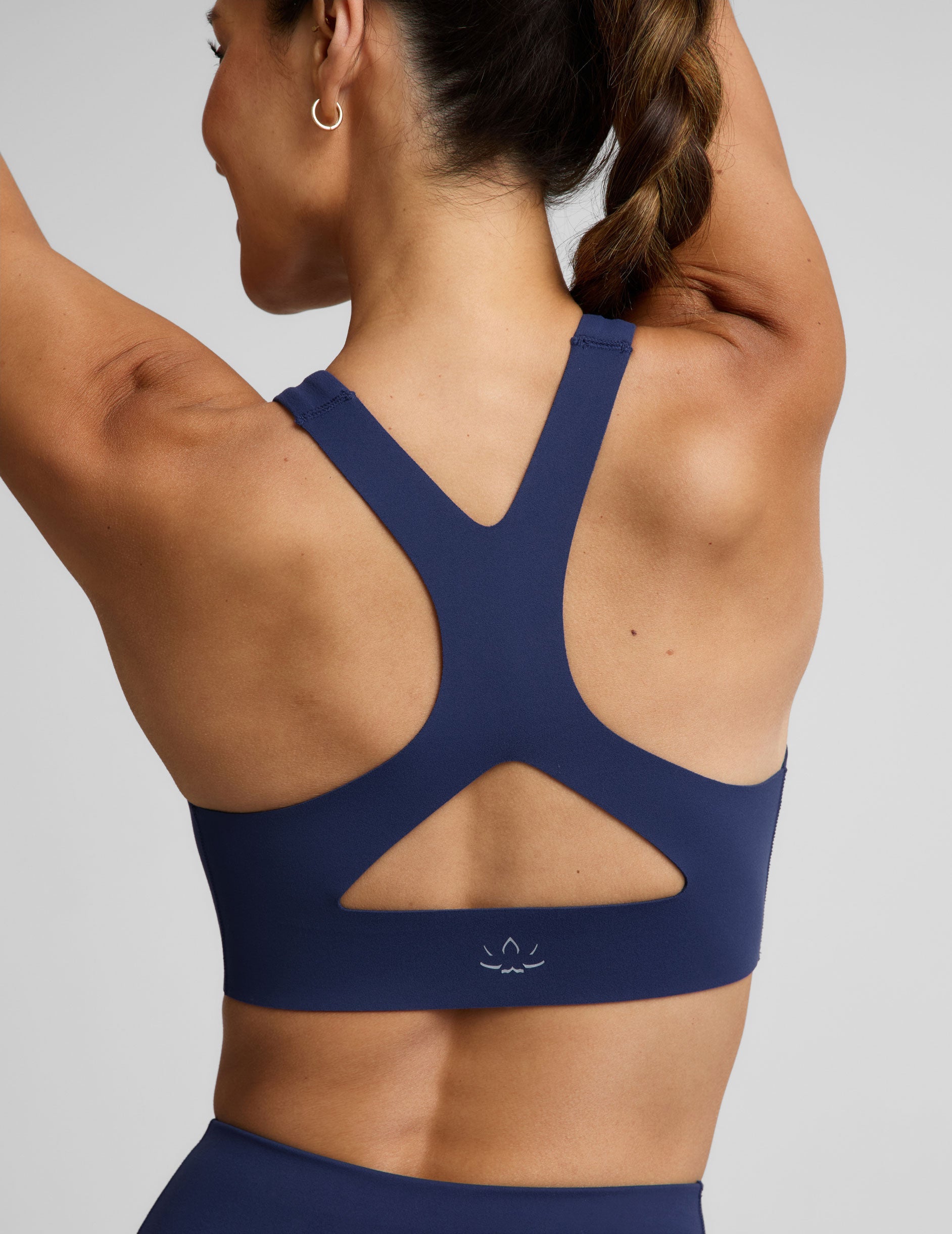 Woman wearing a blue sports bra and blue biker shorts against a plain background.